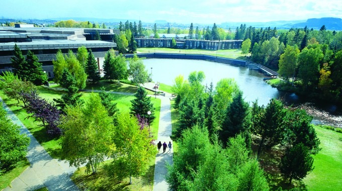 campus universitario con lago y árboles al fondo