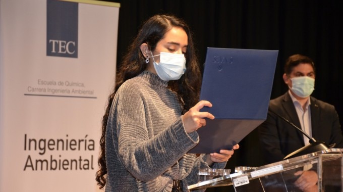 Estudiante sostiene y lee el certificado de acreditación.