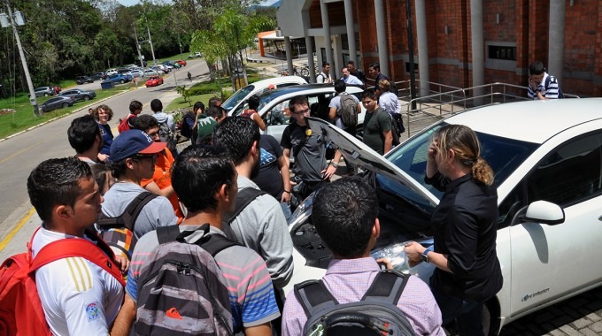 Jóvenes alrededor de un auto eléctrico.