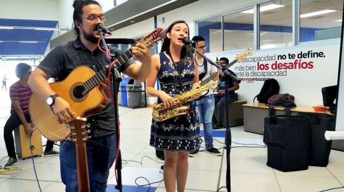 Un estudiante con guitarra y una estudiante cantando.