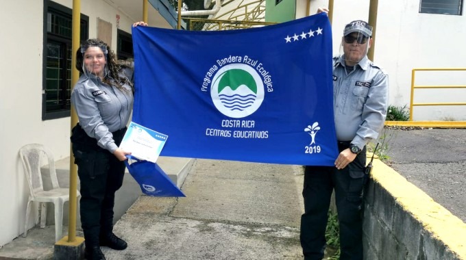 Dos guardas muestran la bandera azul del galardón.