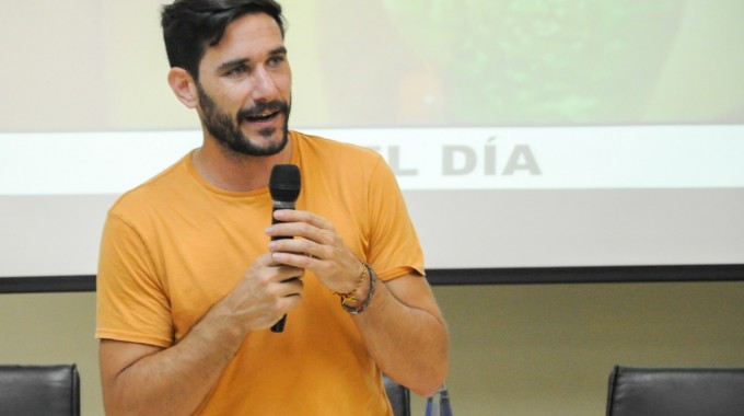 Hombre con un micrófono frente a muchos estudiantes dando una charla.