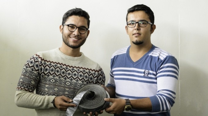 Imagen de dos hombres mostrando una cinta conductora de electricidad.