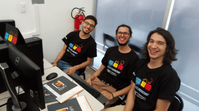 jovenes_programadores_sonriendo_sentados_frente_a_computadora_durante_competencia_