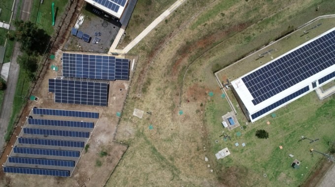 Vista aérea de los paneles solares, tanto en piso como en el tejado de un edificio.