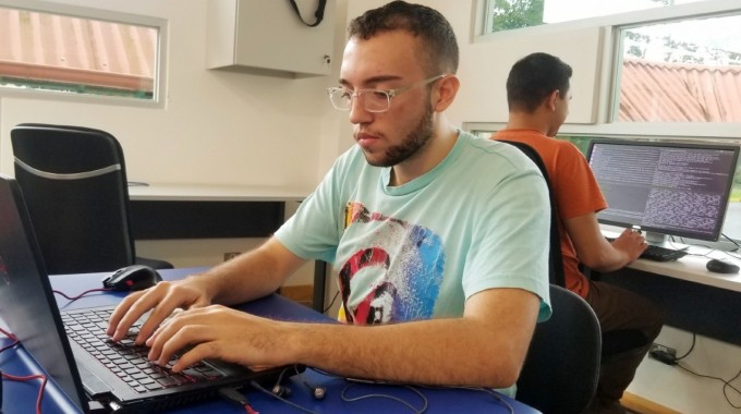 Dos estudiantes en computadoras escribiendo código.
