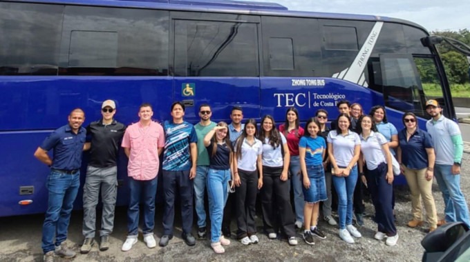 Imagen de varias personas junto a un autobus.  Las personas van rumbo a Parismina.