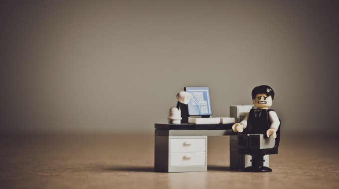 Figura de LEGO de un empresario desesperado frente a su escritorio