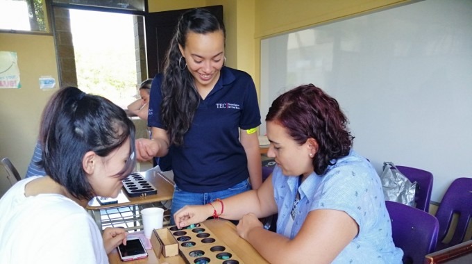 Imagen de una estudiante del TEC, una mamá y su hija aprendiendo matemática por medio de juegos.