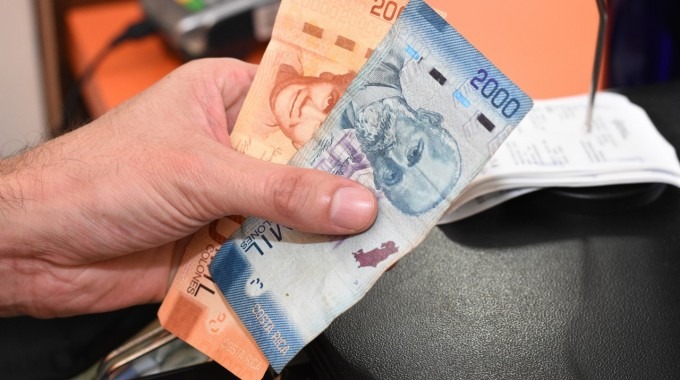 mano con unos billetes y al fondo, un datáfono