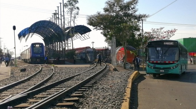 Se observa el tren en la estación y el bus en la parada. 