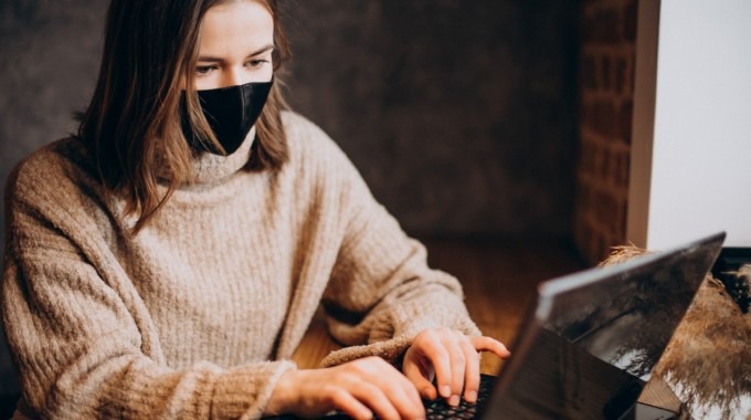 mujer con barbijo frente a computadora