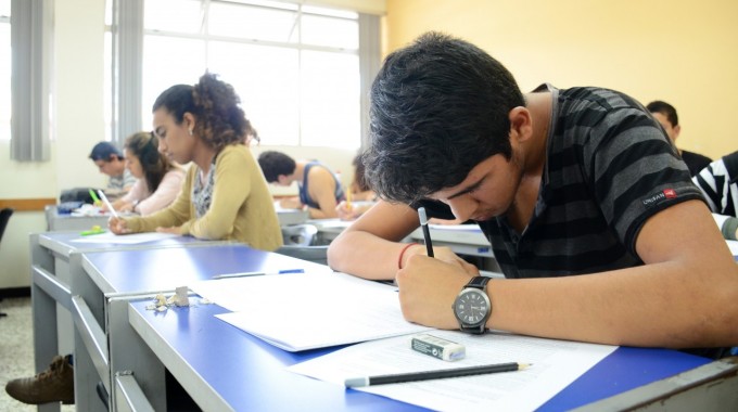 Imagen de varios estudiantes (hombres y mujeres) realizando un examen en un aula.