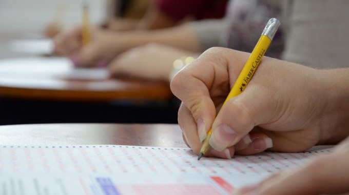 Imagen de una estudiante realizando el examen de admisión. En la fotografía se detalla la mano  con el lápiz.