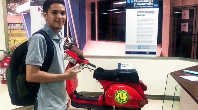 Un joven frente a la moto antigua que forma parte de la exposición