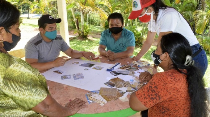 Varias personas sentadas en una mesa, con recortes de papel