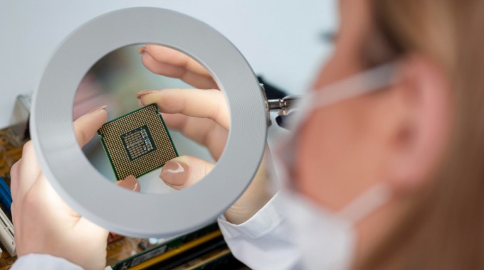 una mujer observa un semiconductor con una lupa