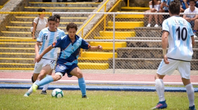 Un joven de la UTN lleva la bola mientras es marcado por un rival de la UCR.