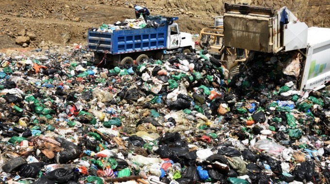 Imagen de un relleno sanitario con dos camiones de basura