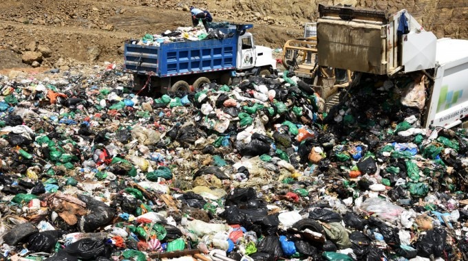 Imagen de un relleno sanitario con dos camiones de basura