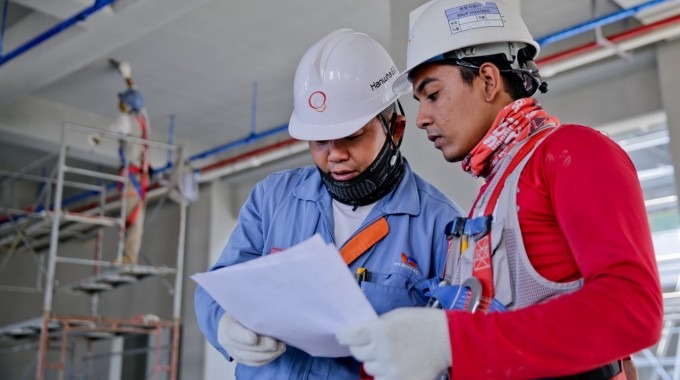 dos hombres en construcción sosteniendo plano