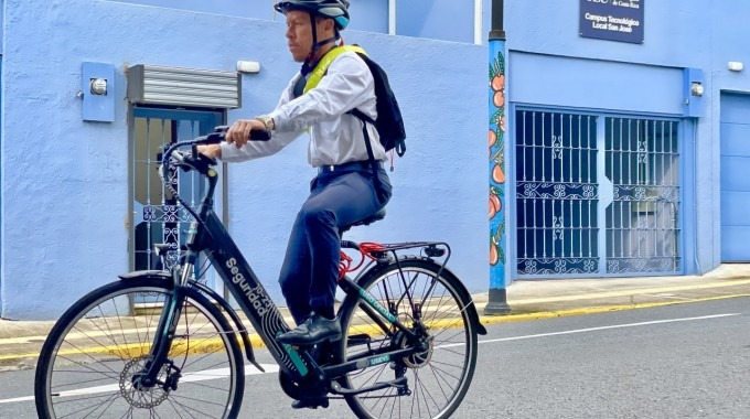 Chofer del TEC monta la bicicleta en la calle, para mostrar como realiza ahora su trabajo.