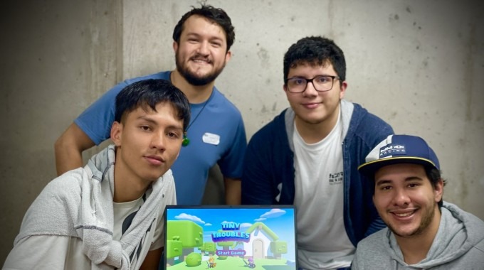 Jóvenes posan mostrando en una computadora el videjuego desarrollado. 