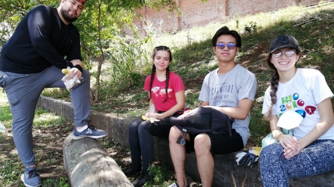 Cuatro estudiantes toman una merienda bajo la sombra de un árbol.