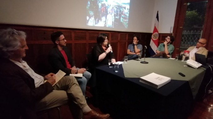 Los expositores y el moderador del conversatorio escuchan la exposición de Zuhra Sasa.