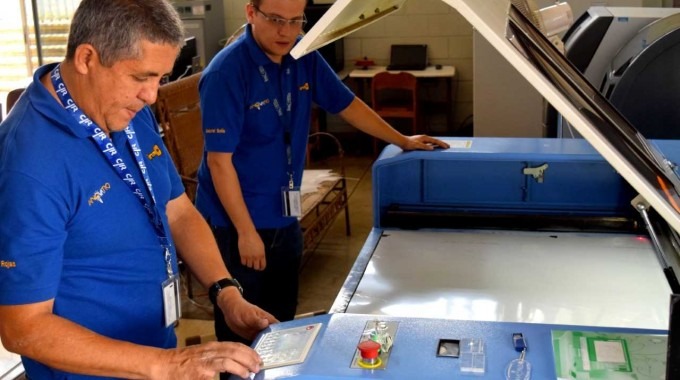 Imagen de dos hombres en una máquina para fabricar caretas protectoras.