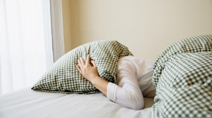 imagen de una mujer con su cabeza bajo la almohada.