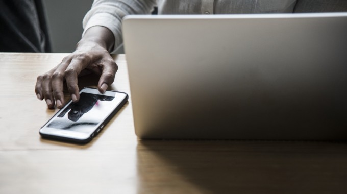 Una mujer en la computadora y usando el teléfono.