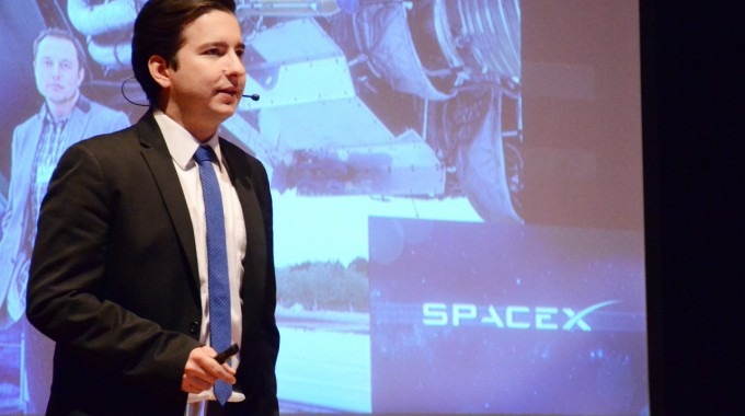 Marco Gómez en el escenario, frente a una proyección que dice SpaceX.