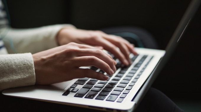 La imagen muestra las manos de una personas tecleando una computadora 