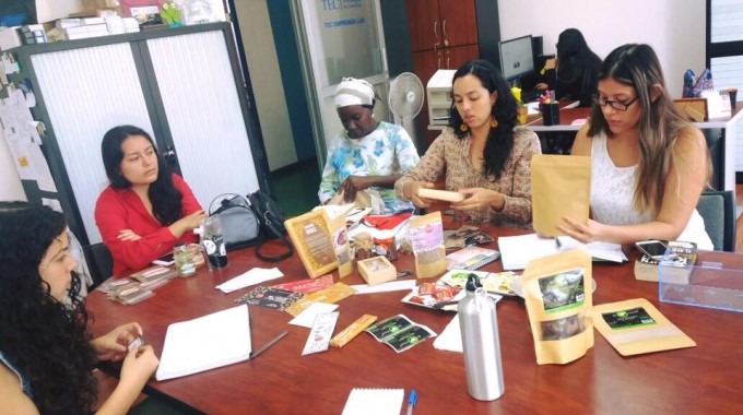 Varias mujeres revisan empaques en una mesa.