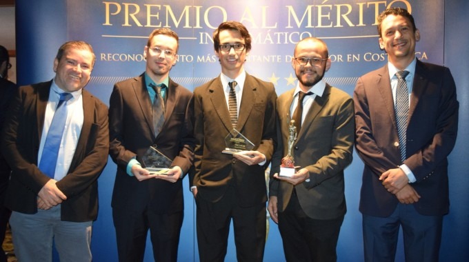 Los cinco ingenieros posan frente a un rótulo de Premio al Mérito Informático.