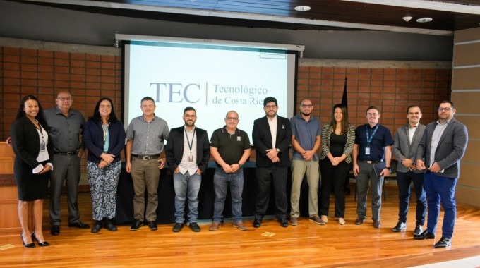 Hombres y mujeres posando en el auditorio, con el logo del TEC de fondo. 