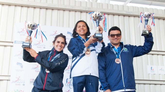 tres personas en un podio alzando los trofeos