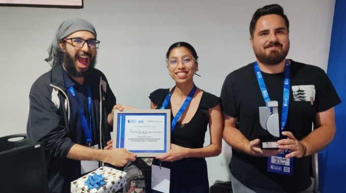 Imagen de tres estudiantes mostrando el premio