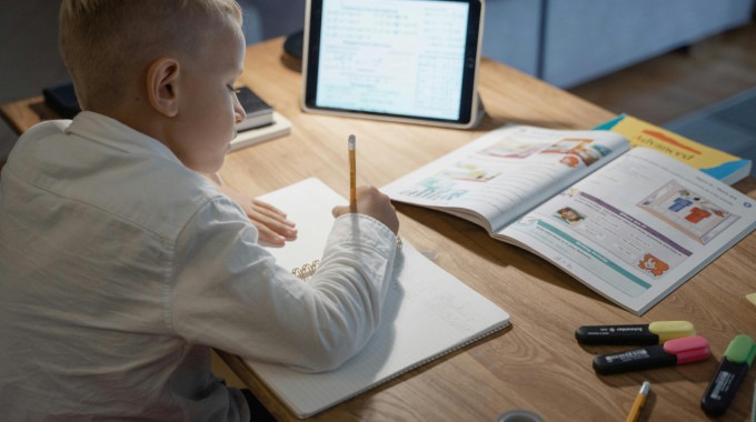 niño estudia con computadora y cuadernos