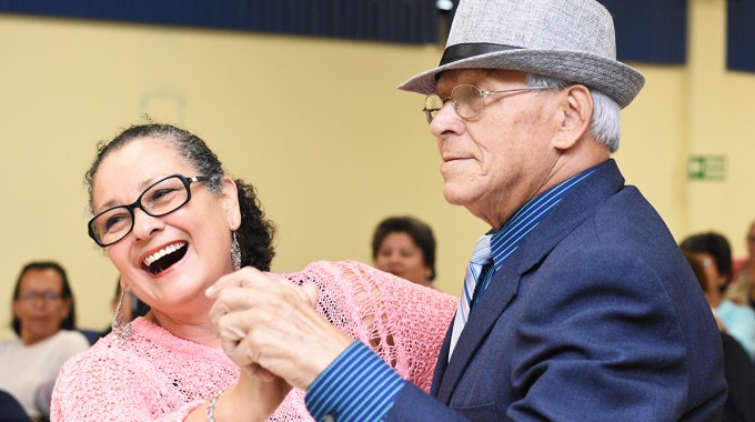 Una pareja de adultos mayores baila tomados de la mano.