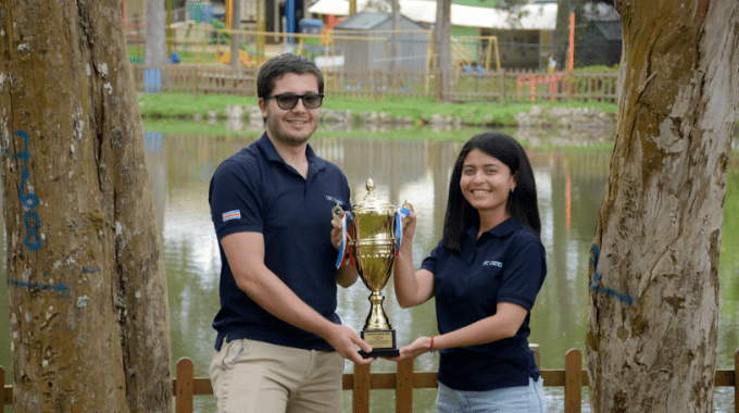 Imagen de dos estudiantes sosteniendo el trofeo