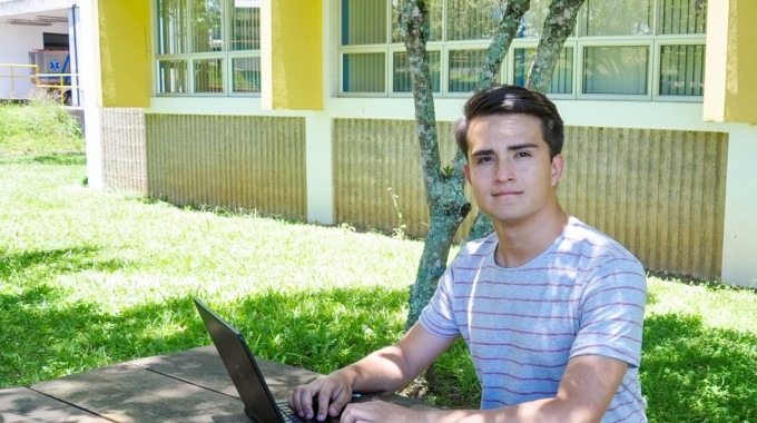 Imagen de un estudiante sentado con la computadora.