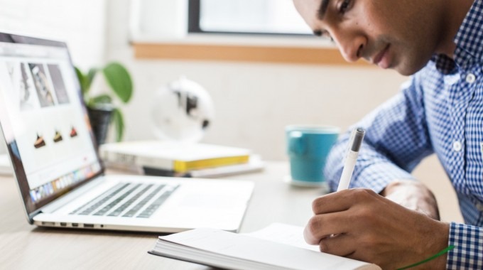 estudiante escribiendo junto a computadora