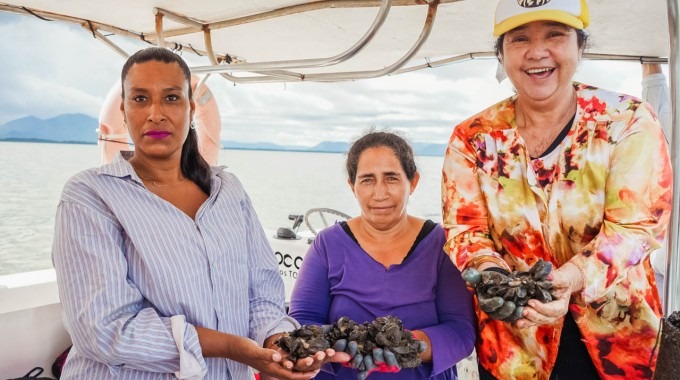 tres mújeres enseñan mejillones recien sacados del mar.