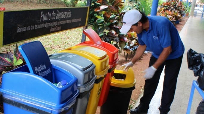 Un hombre saca desechos de un recipiente de reciclaje.