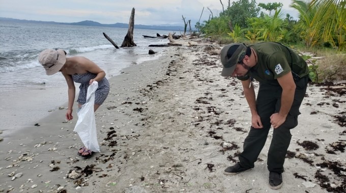 imagen de dos personas juntando residuos de la playa