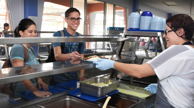 Dos estudiantes esperando que le sirvan almuerzo en el Restaurante Institucional del TEC.