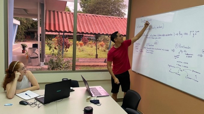 Un joven explica en la pizarra a una estudiante.