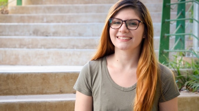 Imagen de una estudiante sentada posando para la fotografía.